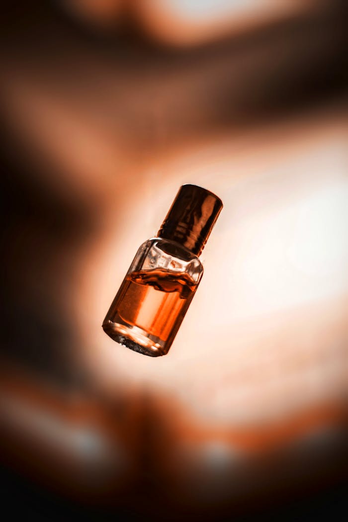 A close-up shot of a glass bottle containing an amber liquid, softly lit.